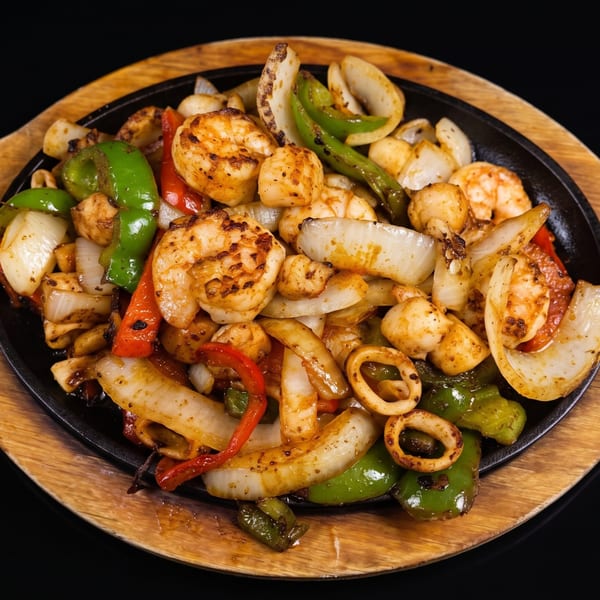 Sizzling fajitas with shrimp, scallops, calamari, onions, and bell peppers on a cast iron plate.